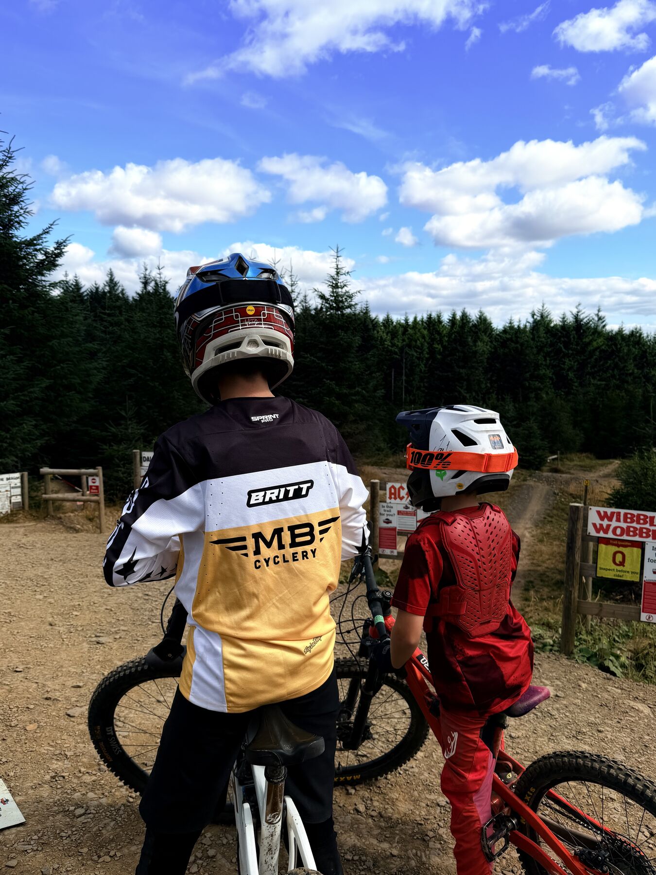Stanlie Britt trailside with a friend, wearing MB Cyclery kit